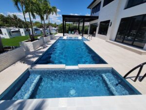 Modern pool and raised spa beside a white home.