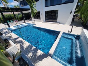 Modern backyard pool and spa beside a white luxury home.