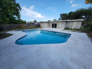 Kidney-shaped pool with stone patio and pool house