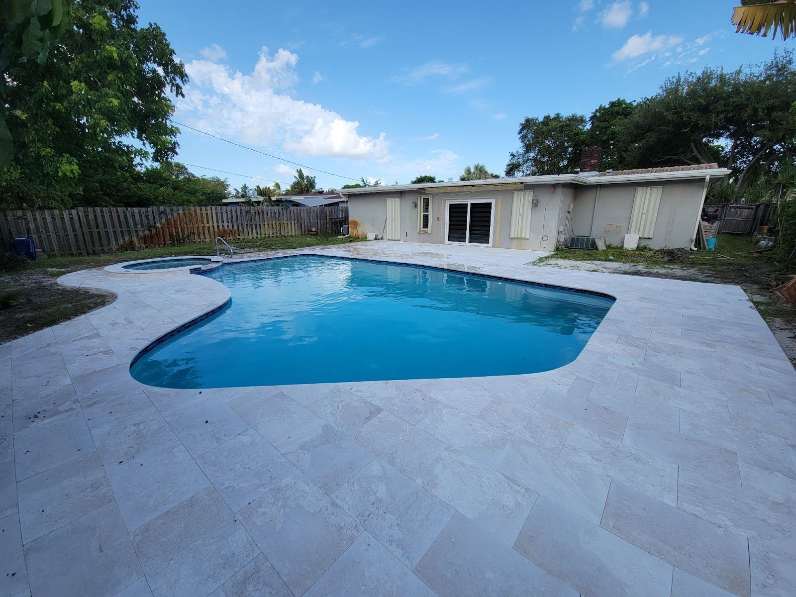 Backyard pool with spa, curved design and tiled patio area