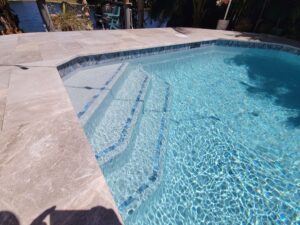 Pool steps with clear blue water and stone coping