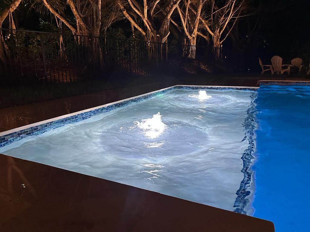 Illuminated backyard swimming pool with water fountains at night