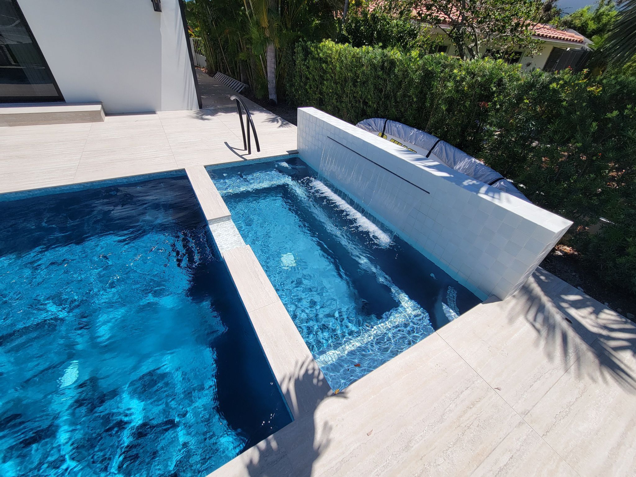 Modern backyard pool with spa and tiled water feature