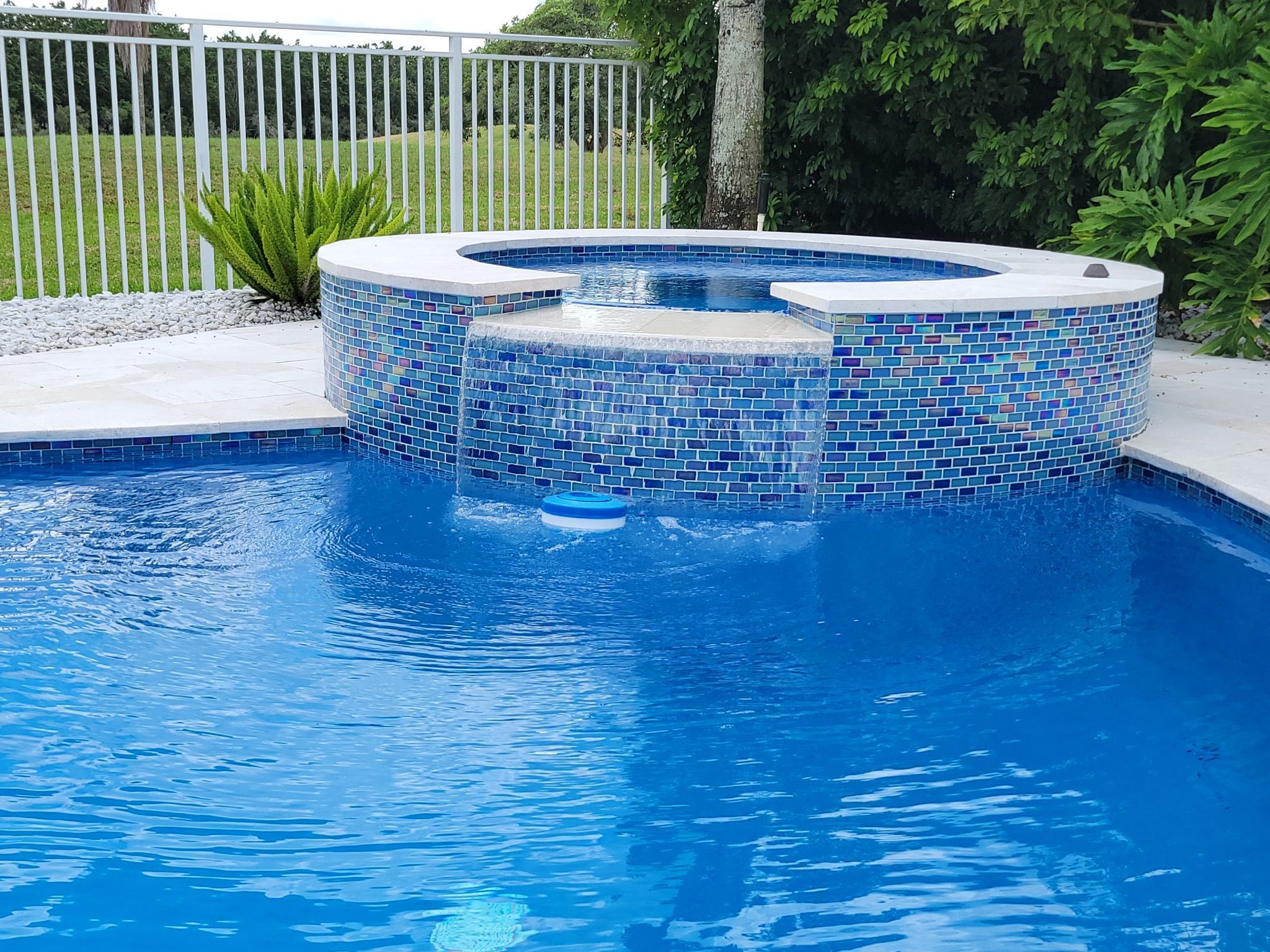 Raised pool spa with blue tile waterfall feature